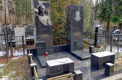 Два памятника похожей формы и надгробный плиты вместо цветника